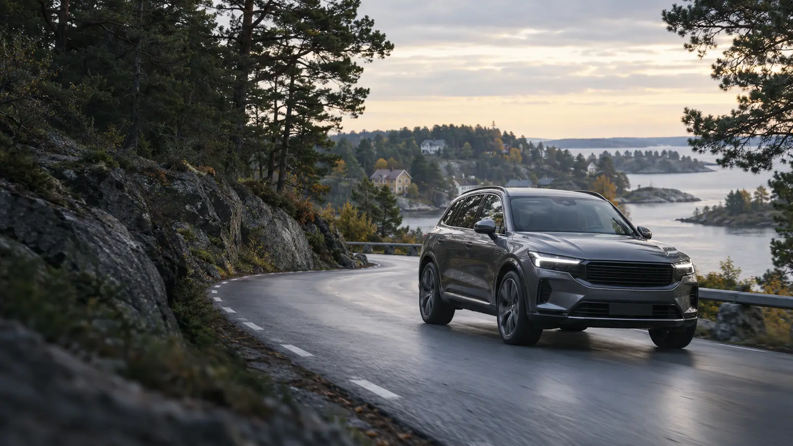 Grå SUV i en kurva på en våt väg genom klippor och tallar, skärgård i bakgrunden